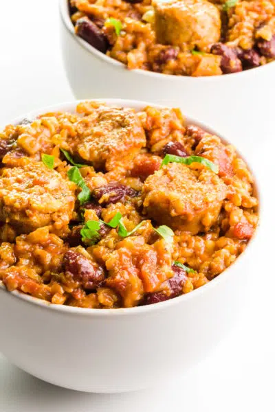 A bowl of vegan jambalaya sits in front of another bowlful.