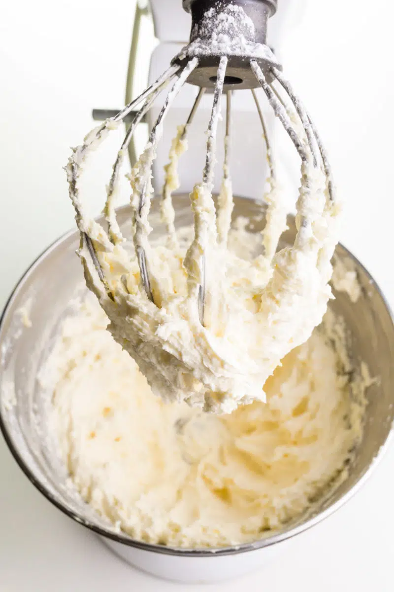 Vegan butter has been whipped in a stand mixer and the attachment and bowl are full of the the mixture.