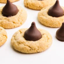 Several vegan peanut butter blossom cookies sit on a white table.
