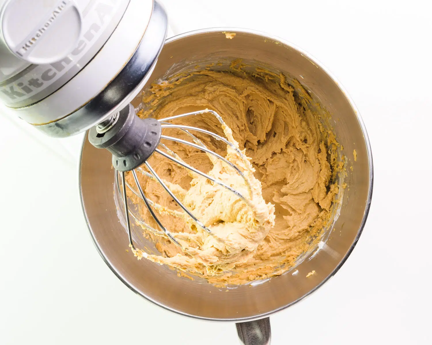 A peanut butter mixture has been whipped with a stand mixer in a mixing bowl.