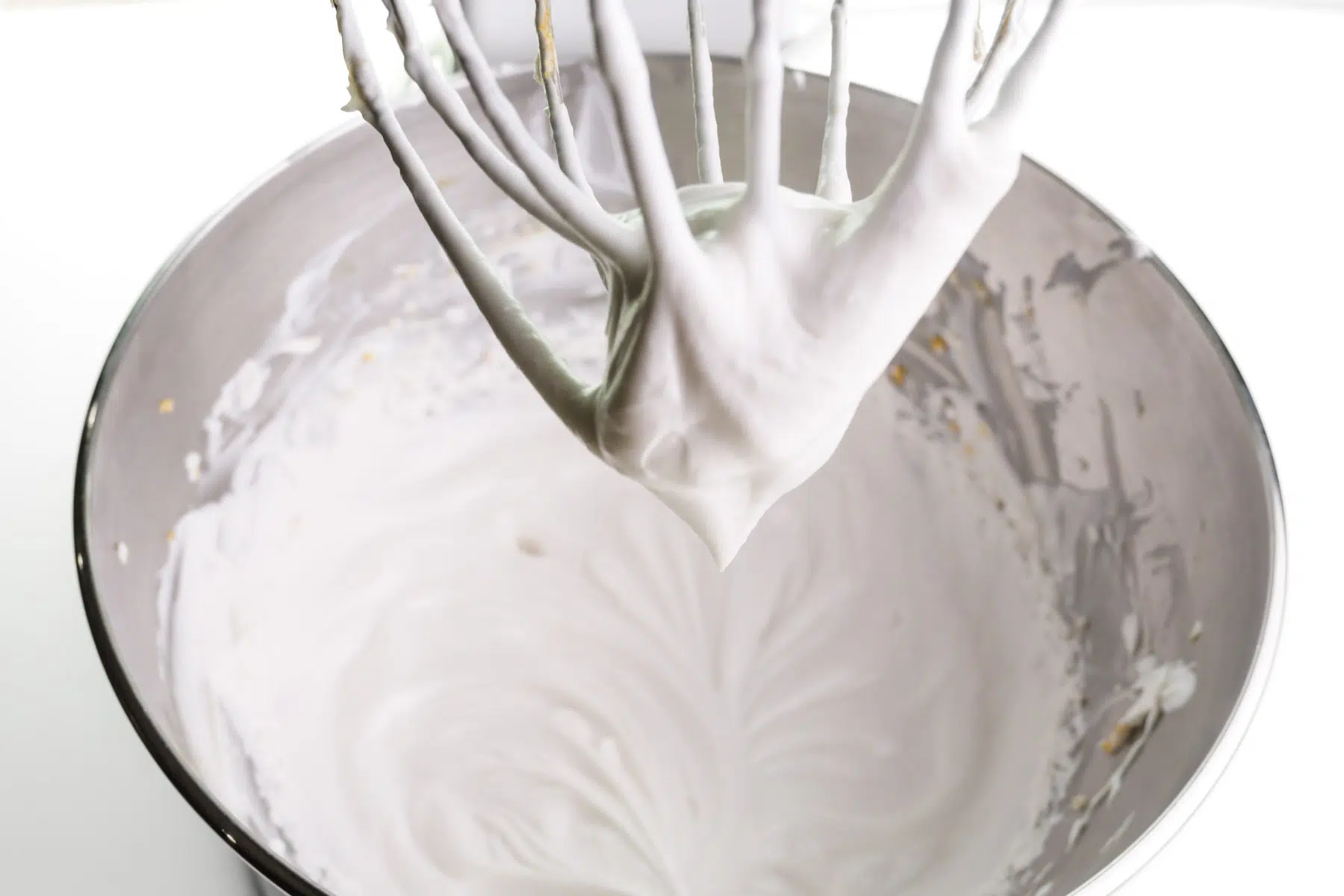 Coconut milk has been whipped using a stand mixer. The beats and the bowl are shown.