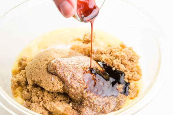 Molasses is being poured into a bowl with other ingredients, such as brown sugar.