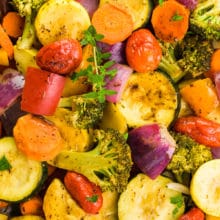 A closeup of vegetarian roasted vegetables with a sprig of fresh thyme in the middle.