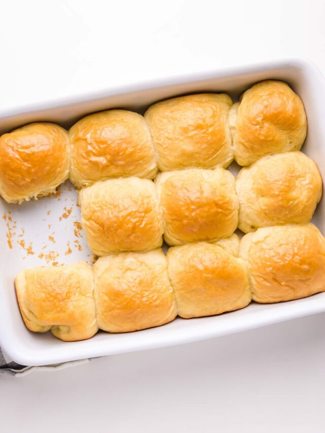 Looking down on a baking dish full of dinner rolls, with one missing.