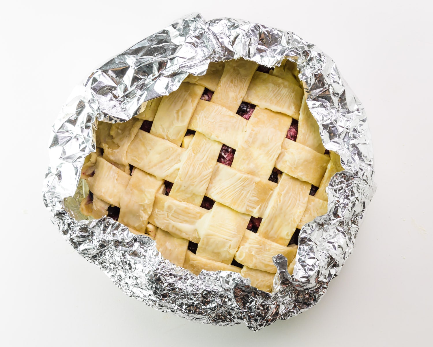 A lattice pie has an aluminum tent around the edges.