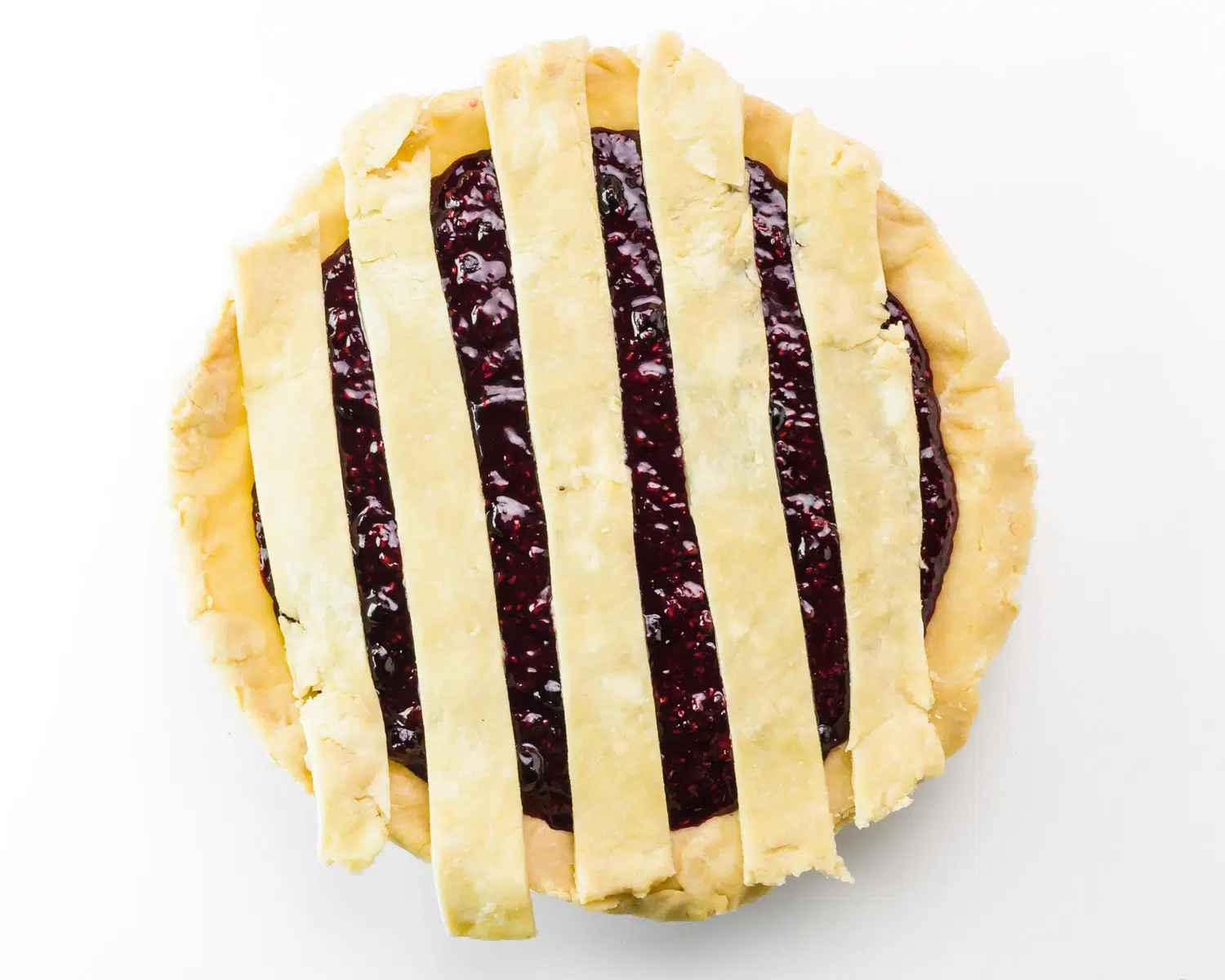 Strips of dough have been added on top of a berry pie.