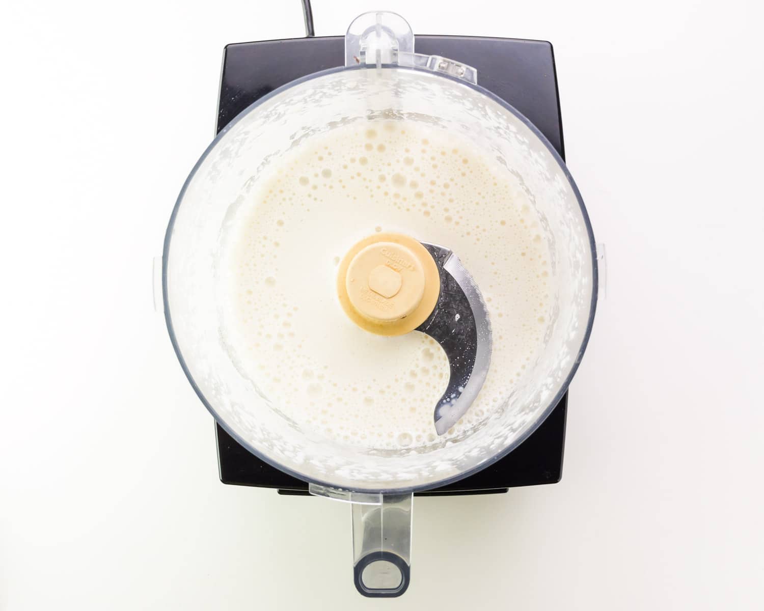 Looking down on a food processor with bubbly soy milk.