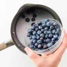 Blueberries are being added to a saucepan with a cornstarch mixture.