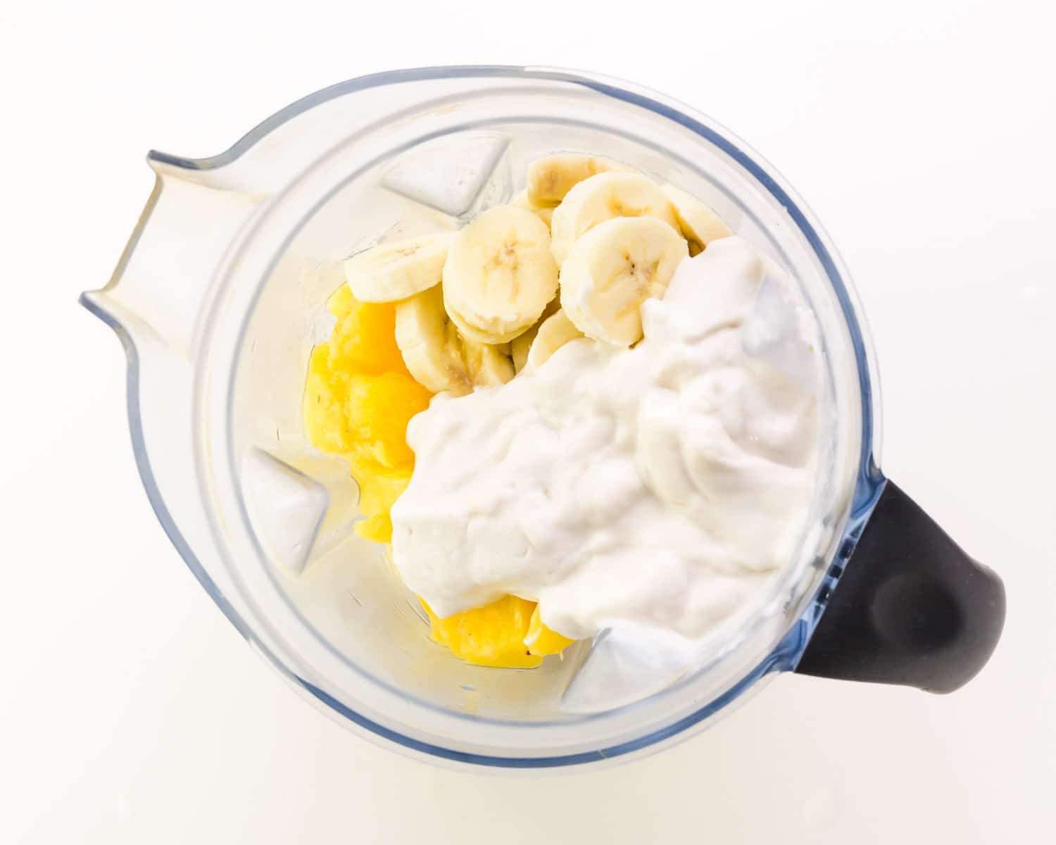 The ingredients are in a blender with pineapple and banana.