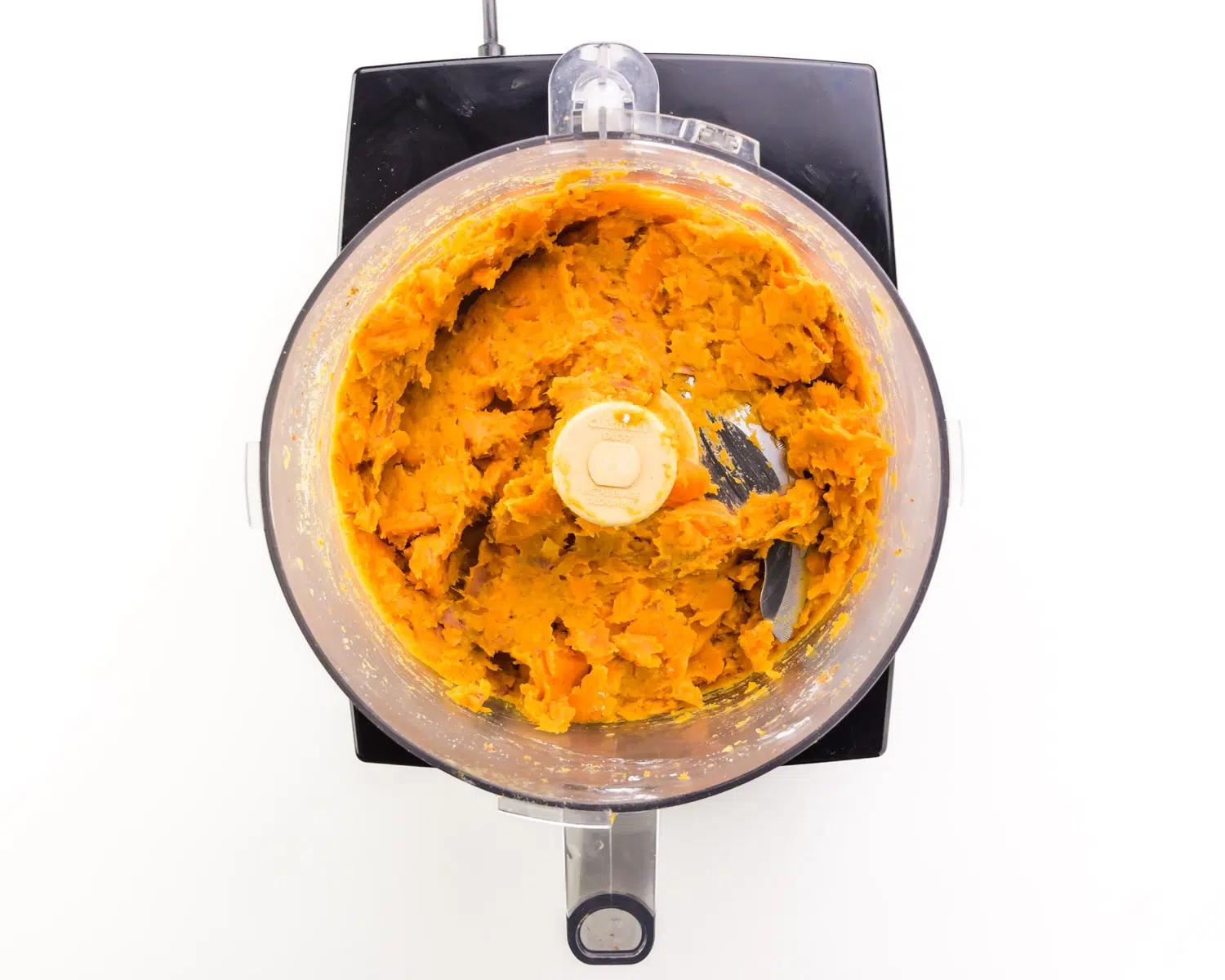 Pulsed sweet potatoes are in a food processor.