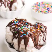 Two bowls of ice cream has chocolate magic shell topping and sprinkles. A bowl of sprinkles sits on the background.