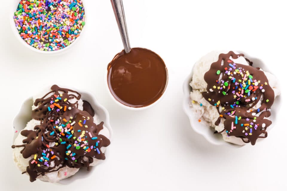 Sitting next to bowls of ice cream with chocolate toppings and sprinkles, staring at the bowl of melted chocolate topping.