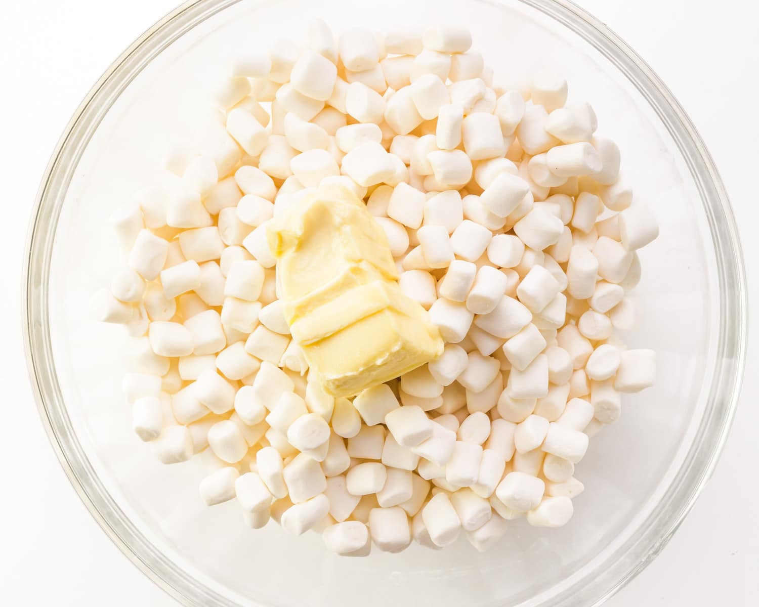 Mini marshmallows are combined in a bowl with vegan butter.