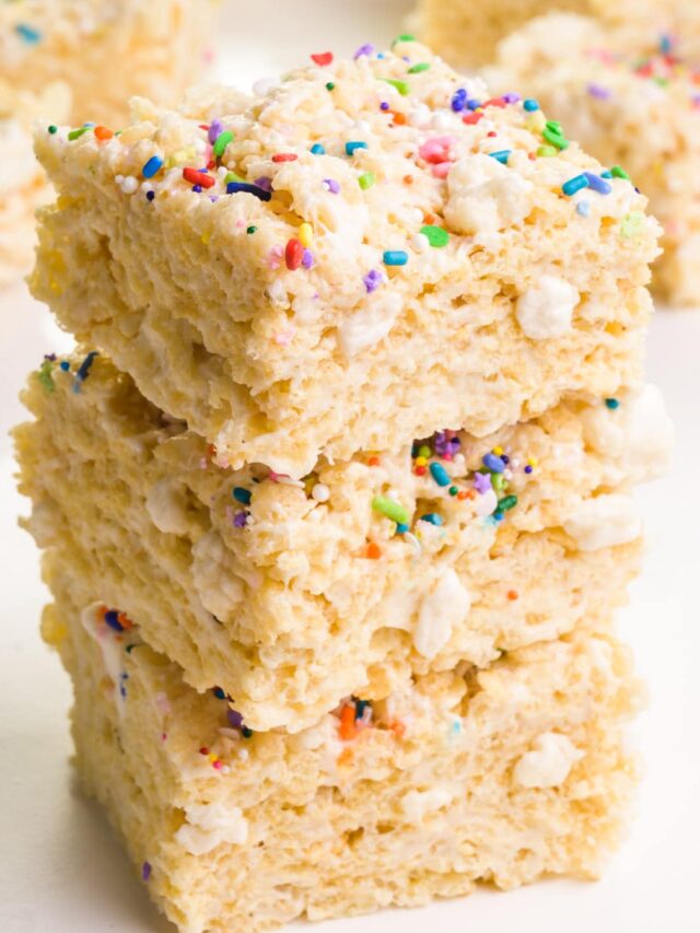 A stack of vegan Rice Krispie treats sits in front of other treats in the background.