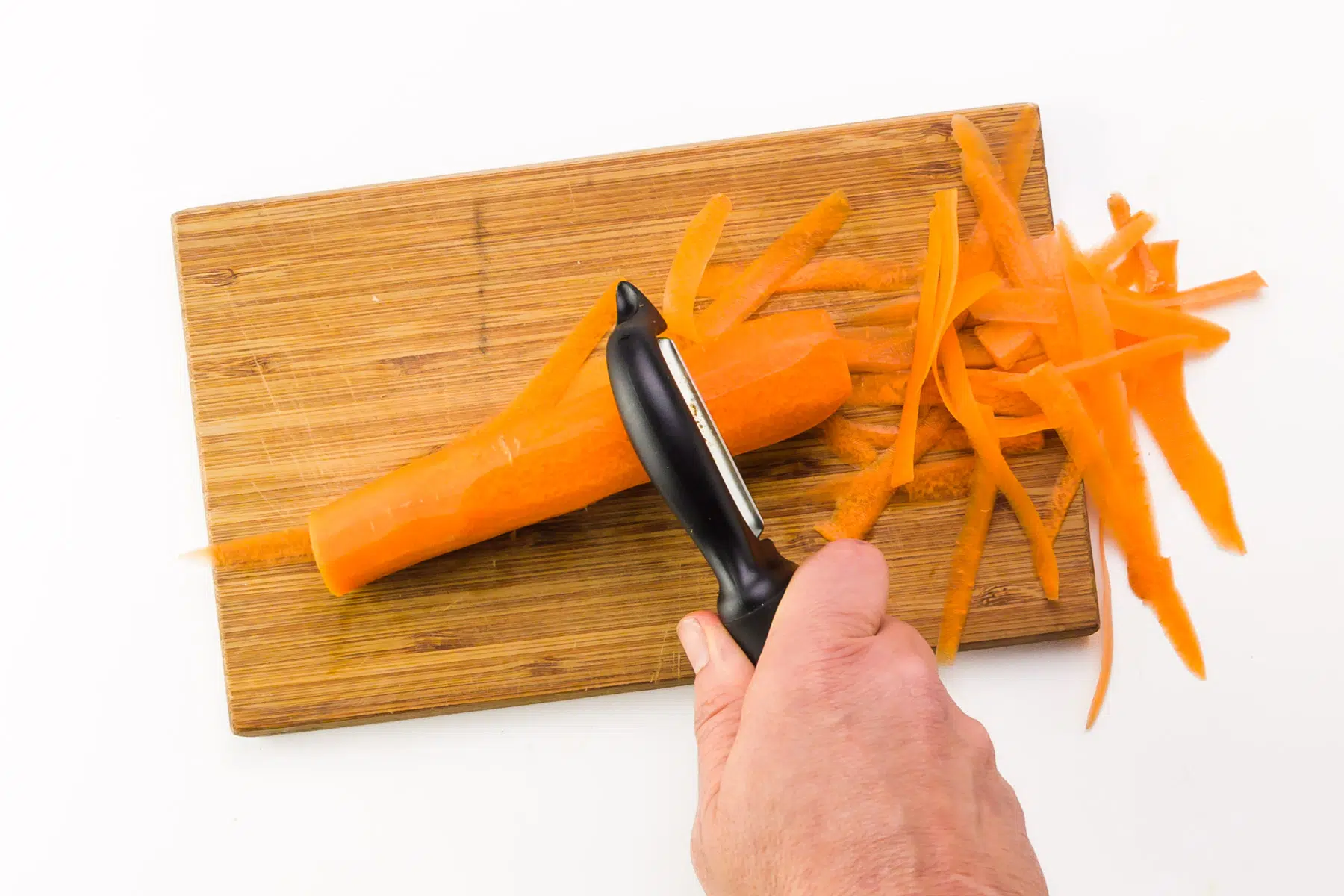 The fat end of a carrot is being shredded to whittle it down.