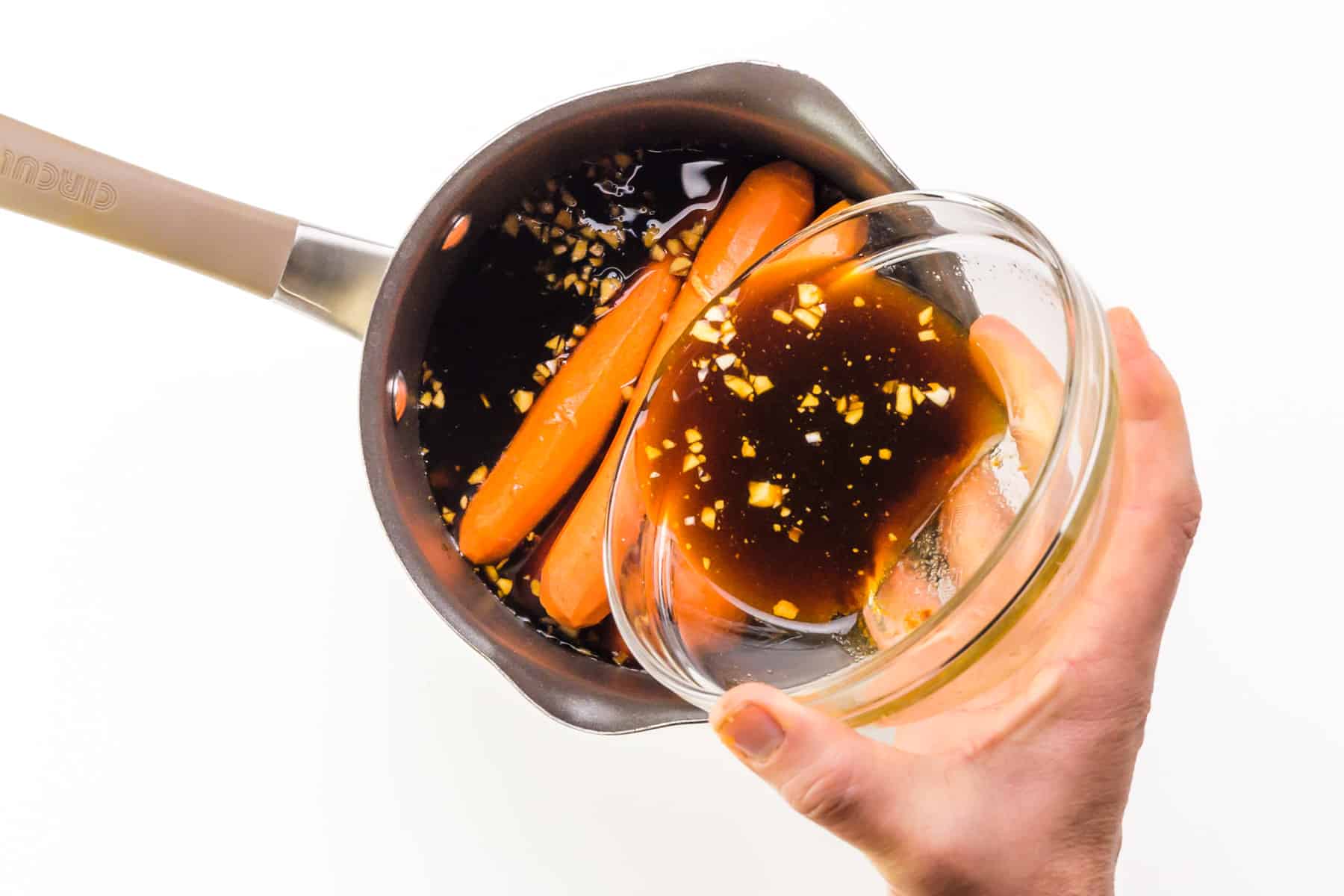 Marinade is being poured over carrots in a saucepan.