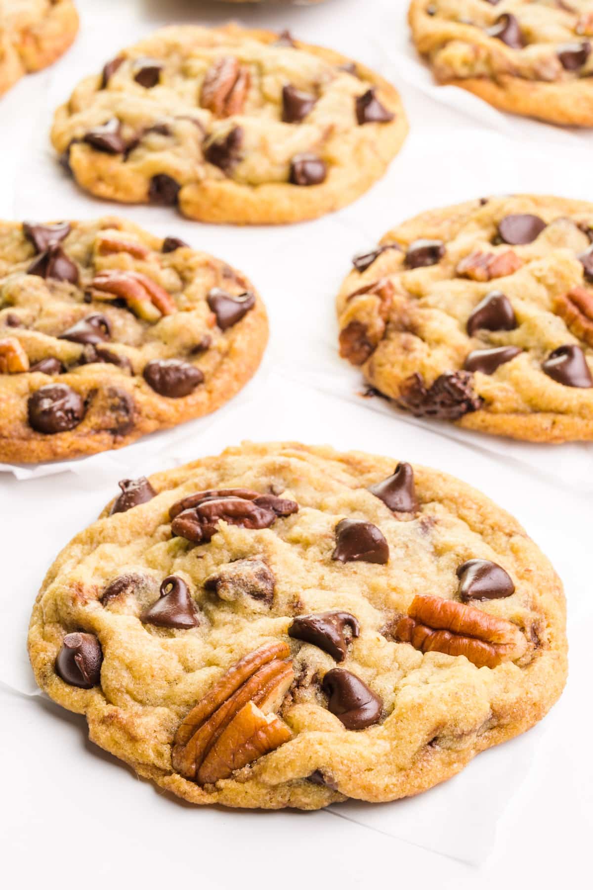 Chocolate chip pecan cookies are placed on a white table.