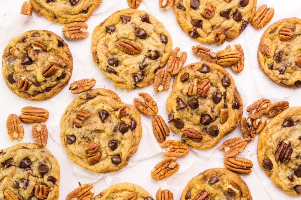 Looking down on chocolate chip pecan cookies on a table with pecans between them.