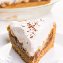 A slice of healthy banoffee pie sits on a plate in front of the rest of the pie in the background.