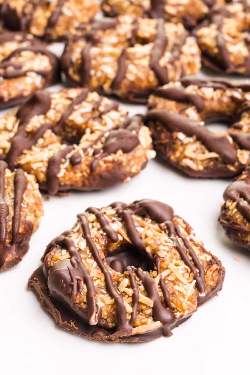 Several dairy-free Samoas cookies sit on a white background.