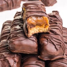 A vegan Twix with a bite taken out sits on top of more Twix bars.