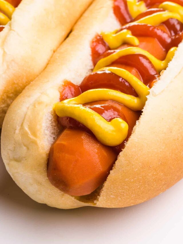 A carrot dog is in a bun and topped with ketchup and mustard.