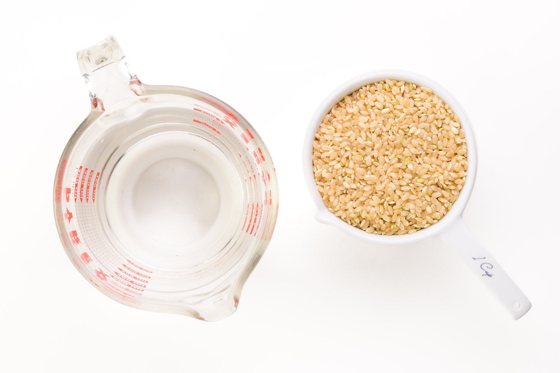 Looking down on water and rice in measuring cups.