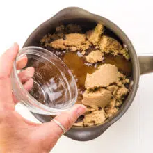 Water is being poured over a saucepan with brown sugar.