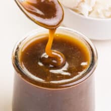 A spoonful of dairy-free butterscotch sauce drizzles over a jar with more sauce.