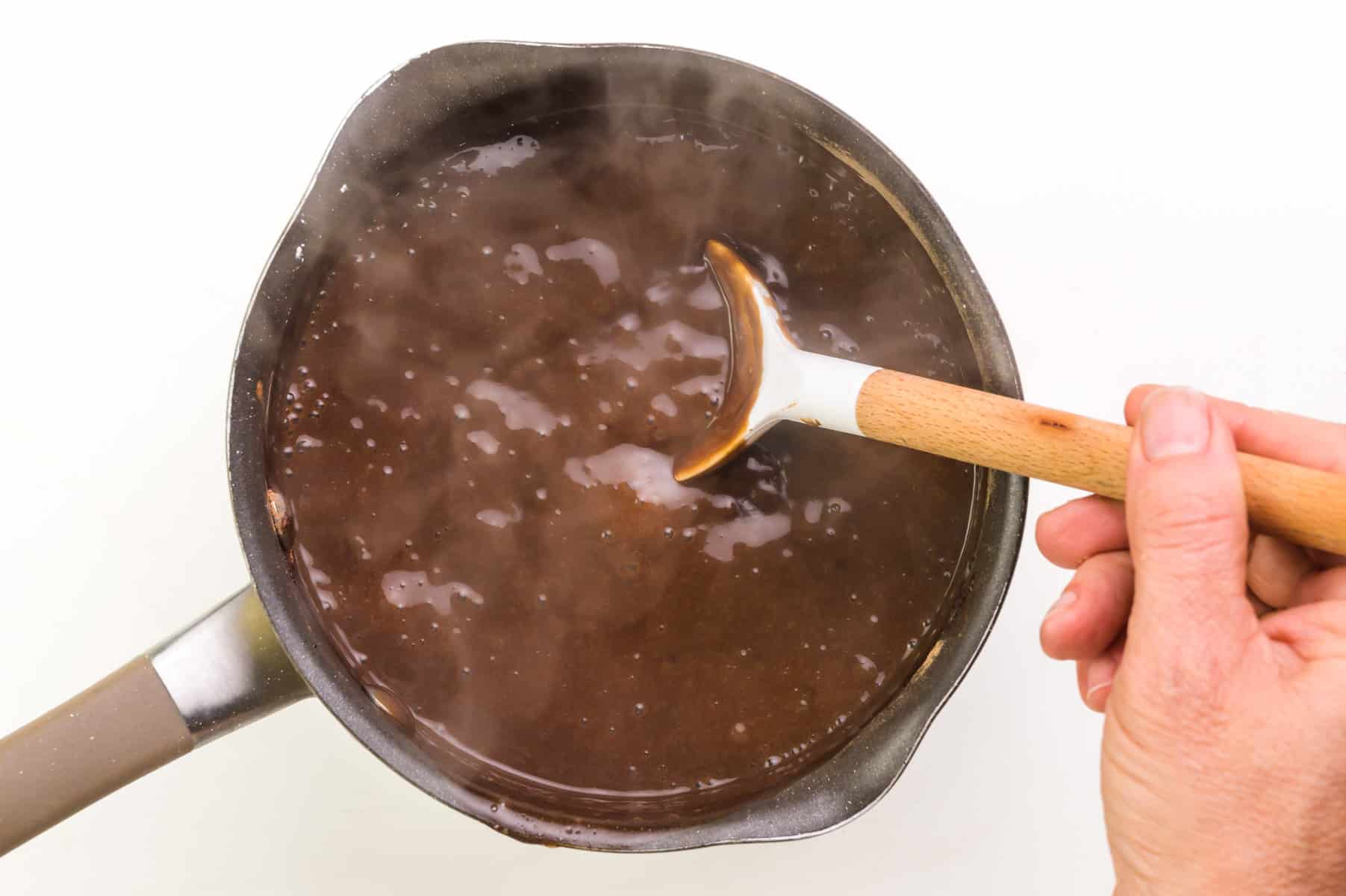 Dairy-free pudding is being stirred in a saucepan.