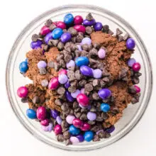 Looking down on a bowl of chocolate cookie dough with colorful candies and chocolate chips on top.