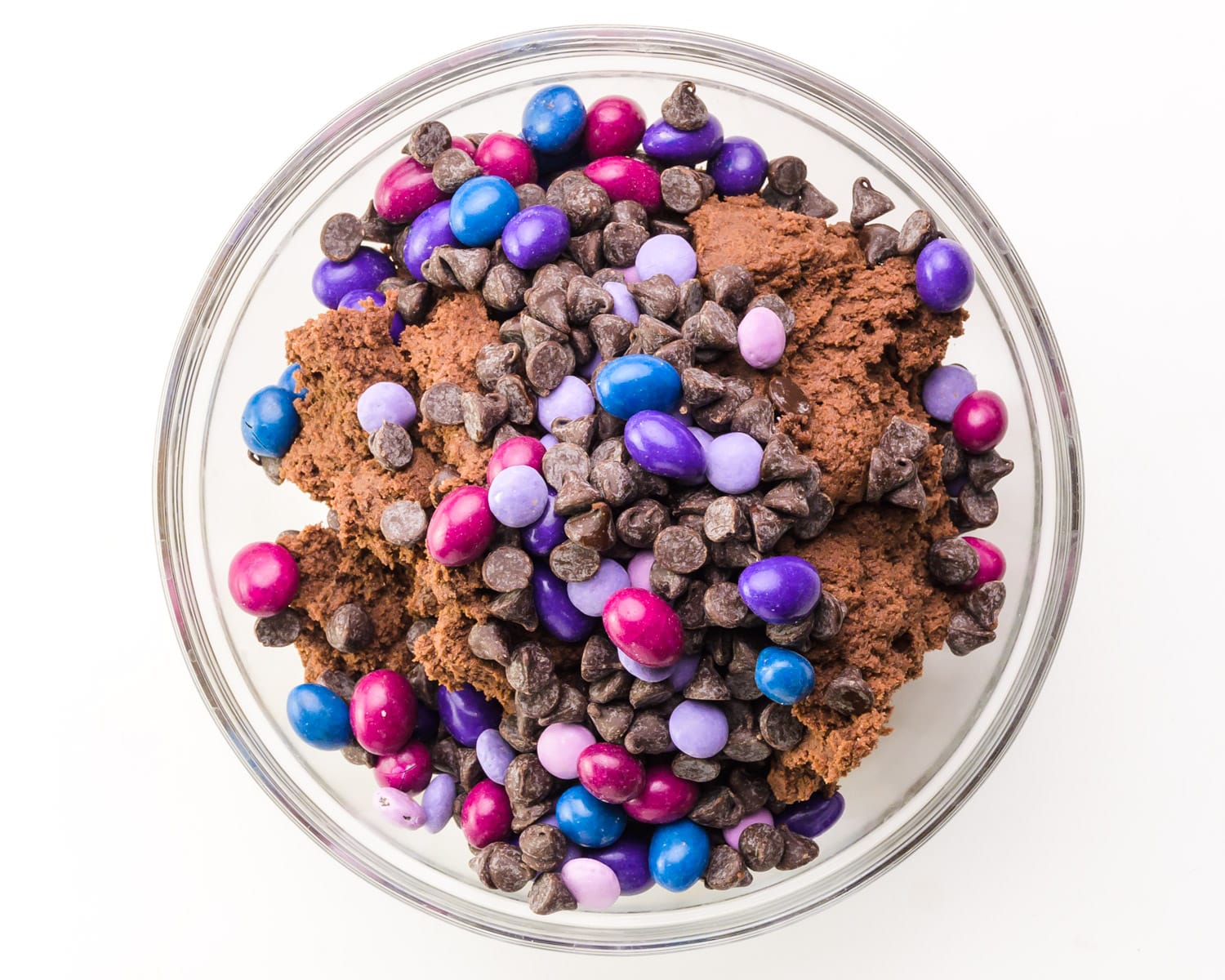 Looking down on a bowl of chocolate cookie dough with colorful candies and chocolate chips on top.