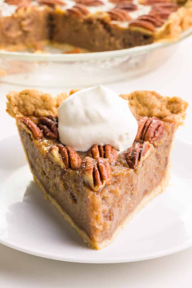 A slice of egg-free pecan pie sits on a plate in front of the rest of the pie.