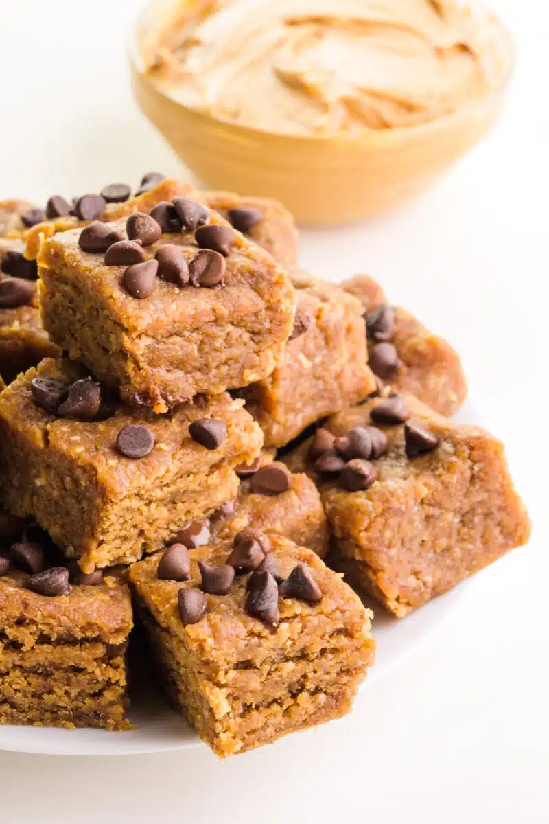 A stack of date-sweetened vegan fudge sits in front of a bowl of peanut butter.