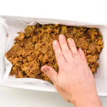 A hand presses down on a fudge mixture in a pan.