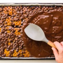A hand holds a spatula, spreading melted chocolate chips in a pan.