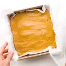 A hand holds a pan full of vegan peanut butter fudge.