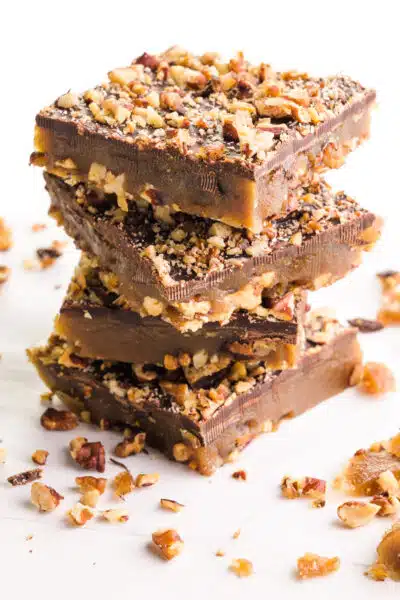 A stack of vegan toffee squares has bits of toffee around it.