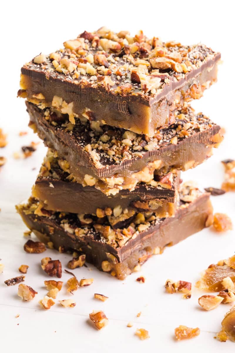 A stack of vegan toffee squares with bits of toffee around them.
