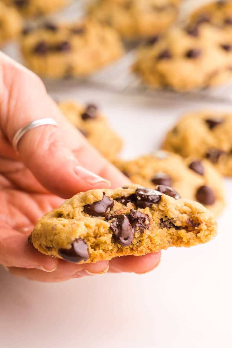 A hand holds a cookie with a bite, revealing lots of chocolate chips.