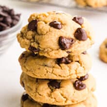 A stack of chocolate chip cookies next to a bowl of chocolate chips.