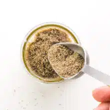 A hand pours chia seeds into a bowl.