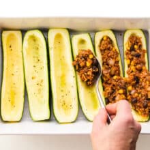 Zucchini boats are being filled with veggie filling.