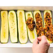 Zucchini boats are being filled with veggie filling.