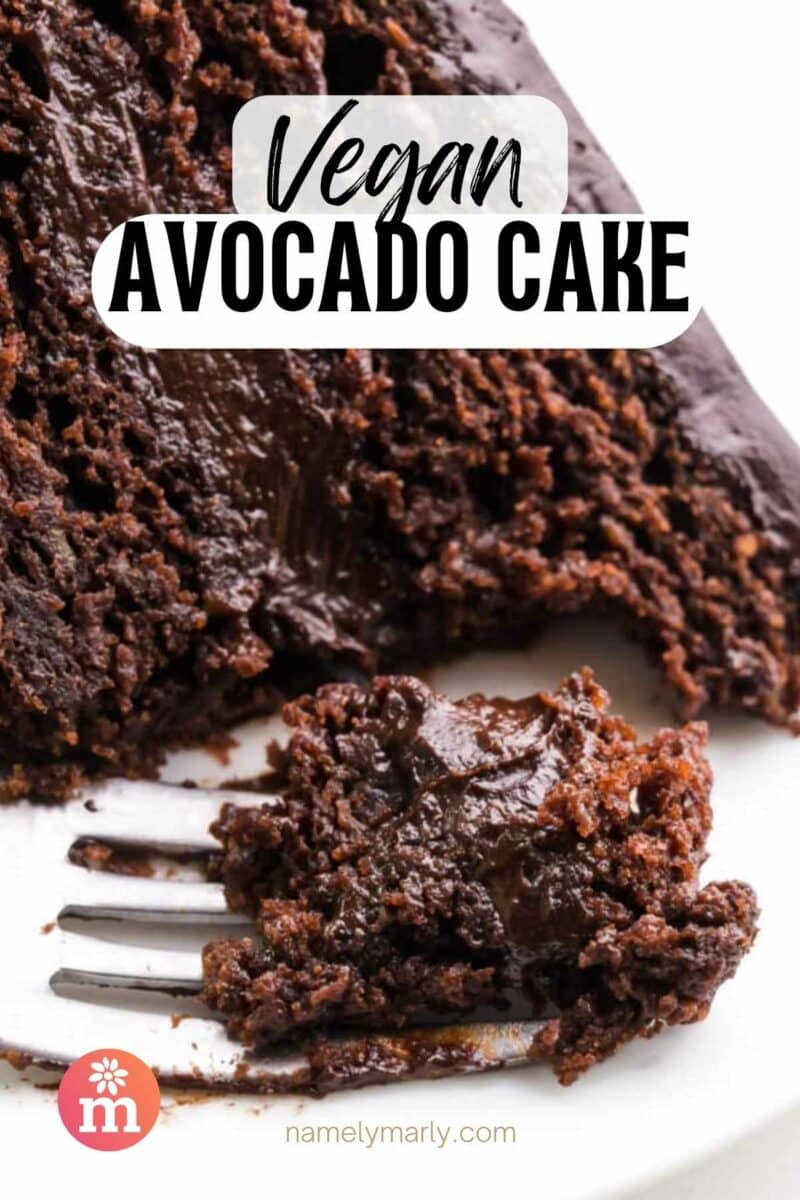 A bite of chocolate cake is on a fork in front of the rest of the cake. The text reads, Vegan Avocado Cake.