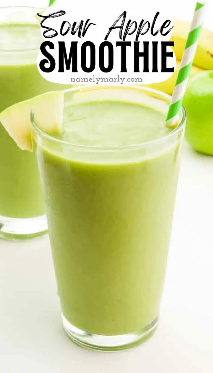 A tall glass of green smoothie has a green straw and an apple wedge. The text reads, Sour Apple Smoothie.