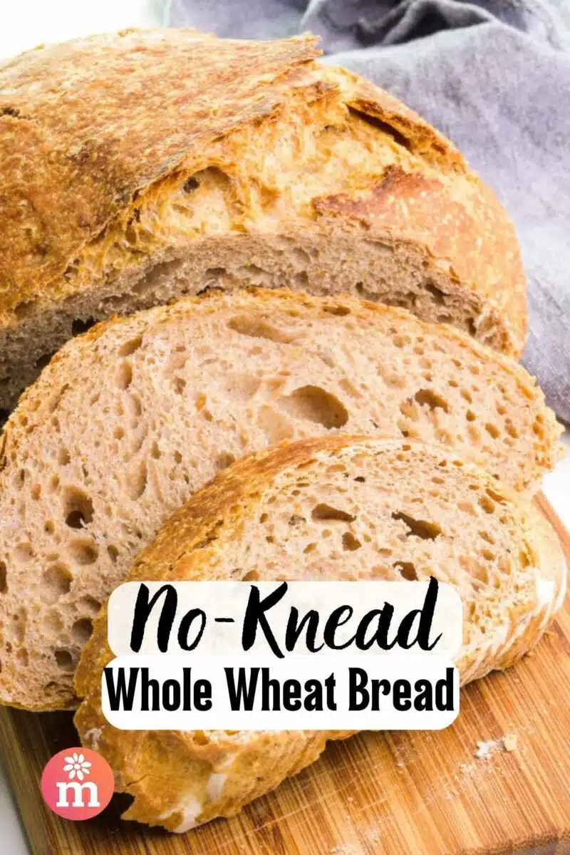 Slices of whole wheat bread sit on a cutting board. The text reads, No-Knead Whole Wheat Bread.