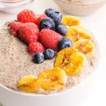 A closeup of hot chia pudding with seared bananas and fresh berries on top.