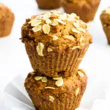 Two applesauce muffins are stacked on top of each other with more muffins behind them.