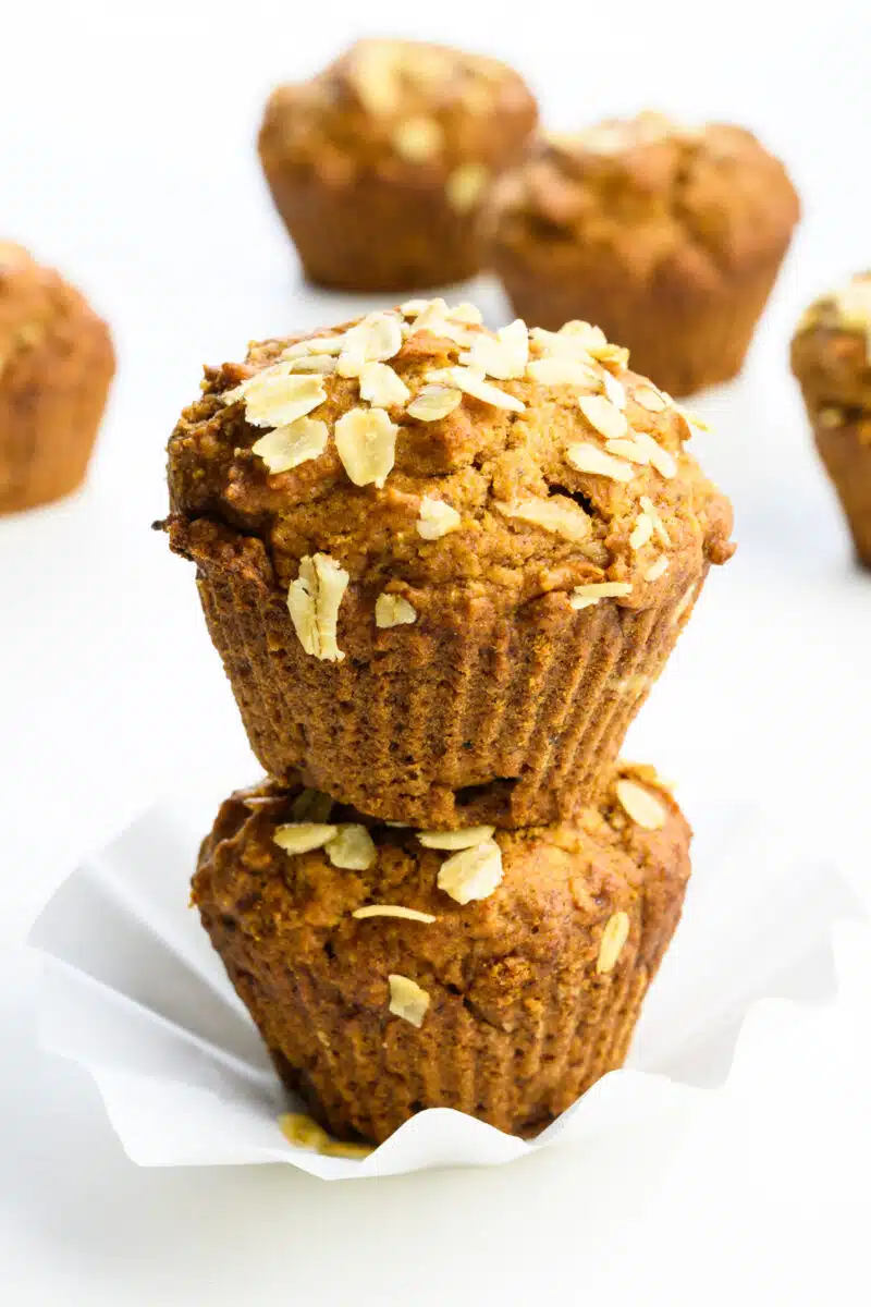 Two applesauce muffins are stacked on top of each other with more muffins behind them.